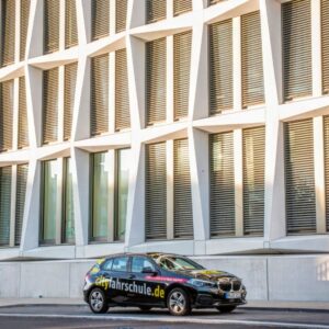 City Fahrschule Auto vor einem Gebäude.