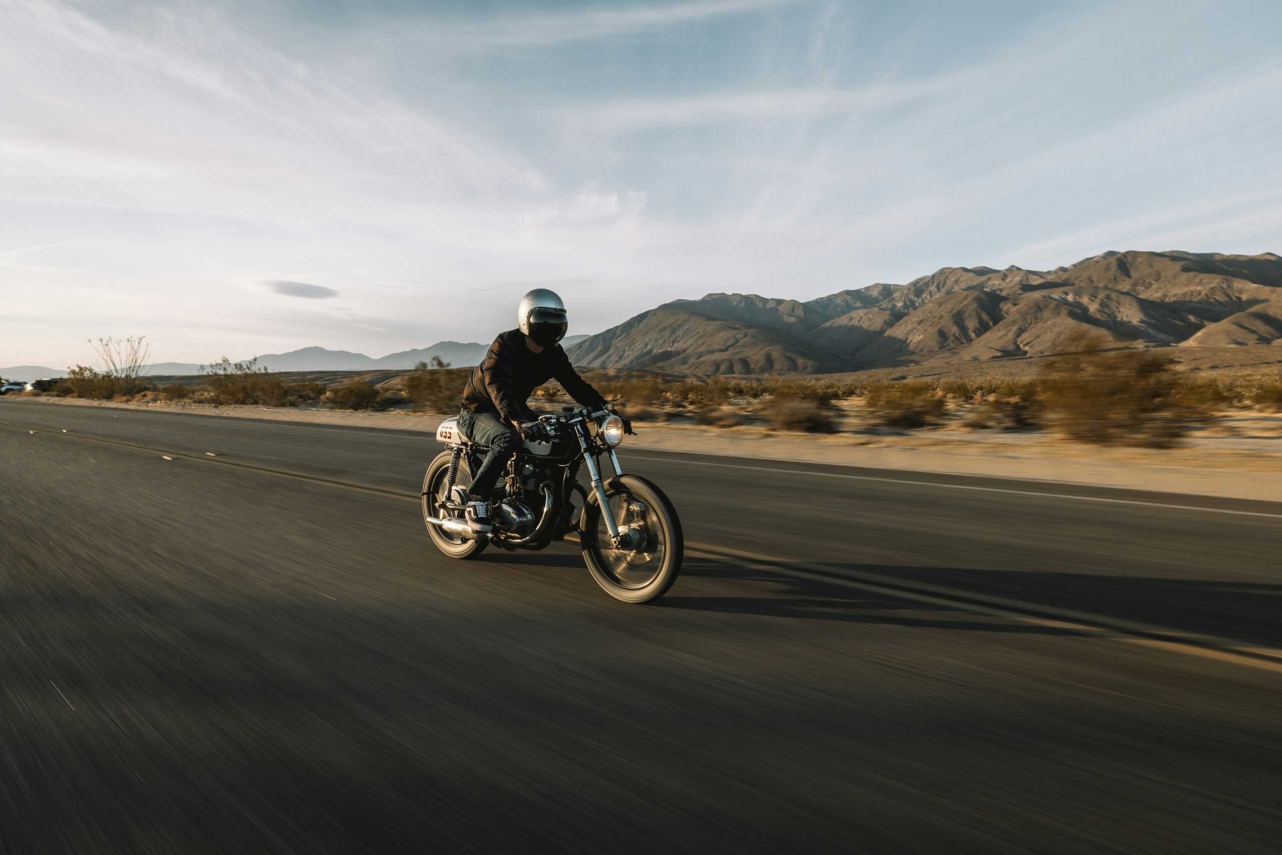 Ein Mann fährt mit seinem Motorrad durch eine weite, leicht bergige Landschaft.