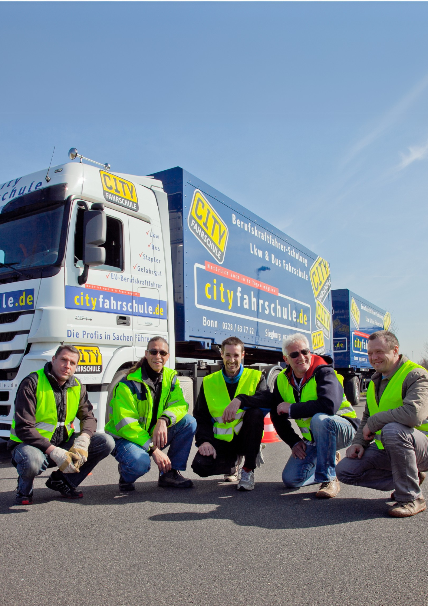 5 Auszubildende vor einem City Fahrschule LKW mit Warnwesten.